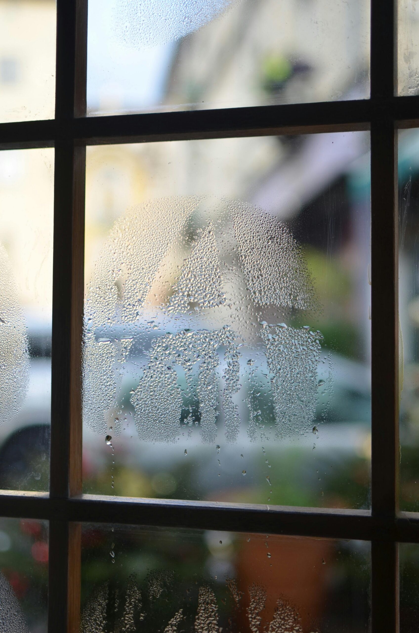 Square shaped frame and misted glass with small water drips in building in daylight