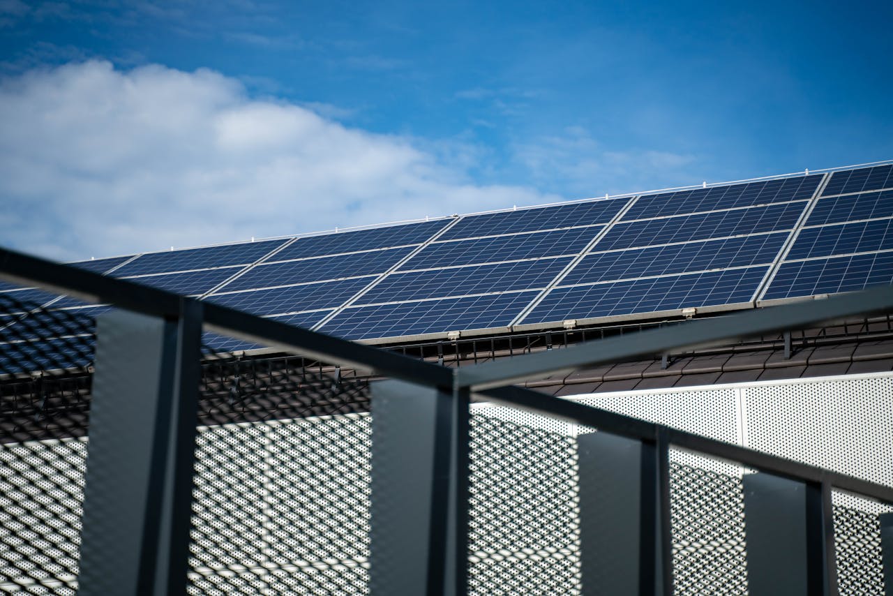 hero-img-02 Close-up view of modern solar panels on a rooftop against a clear blue sky, representing clean energy.
