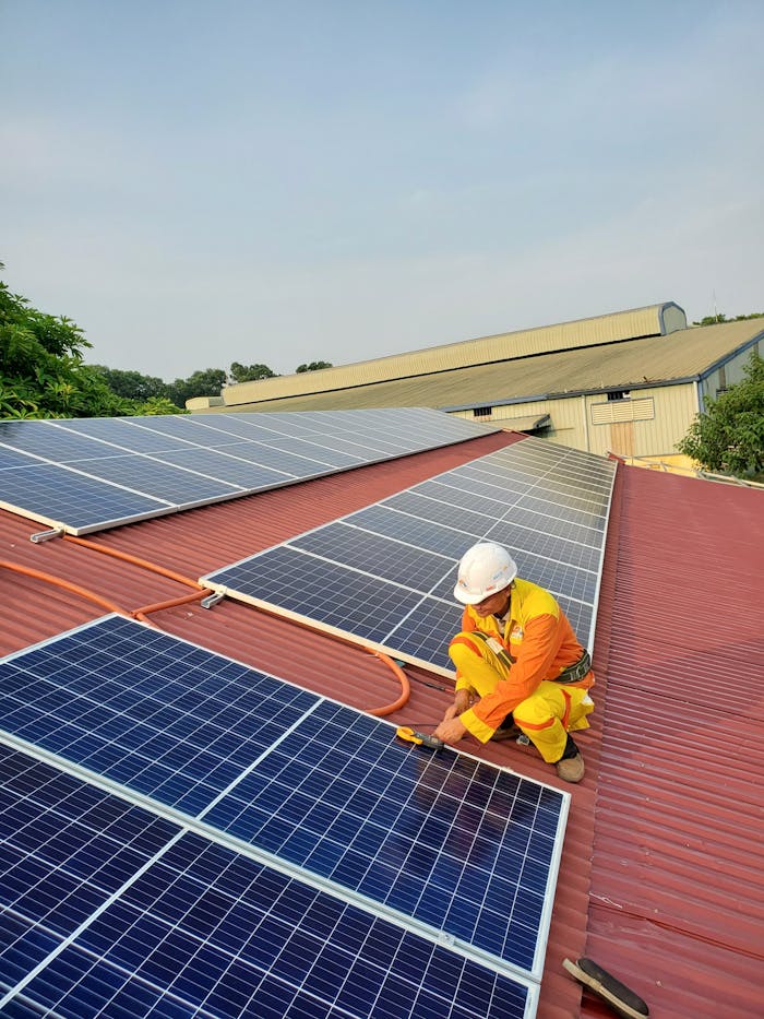 services-02 Technician working on solar panel installation on a rooftop under clear sky.