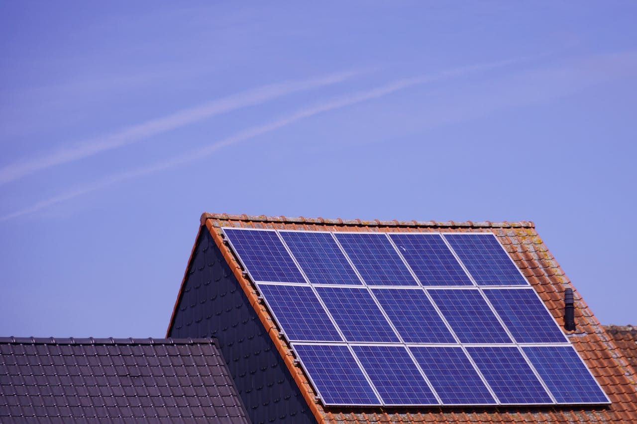 gallery-1 Close-up of solar panels on a tiled rooftop under a clear sky, showcasing renewable energy.