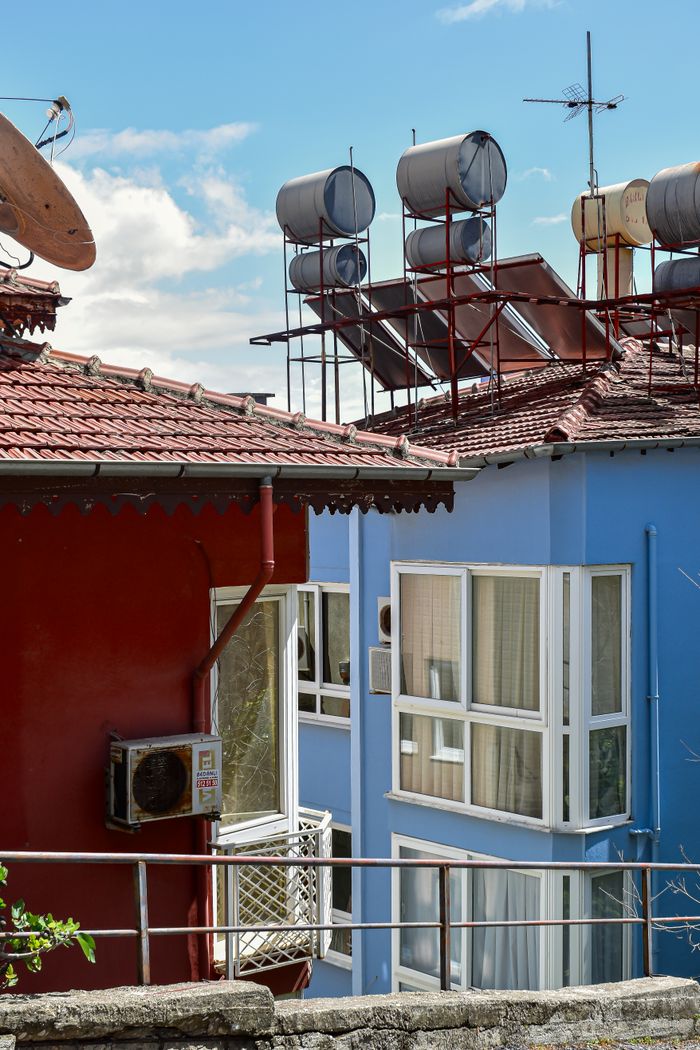 services-02 Colorful rooftops with solar water heaters in sunny urban setting. Ideal for energy or architecture themes.