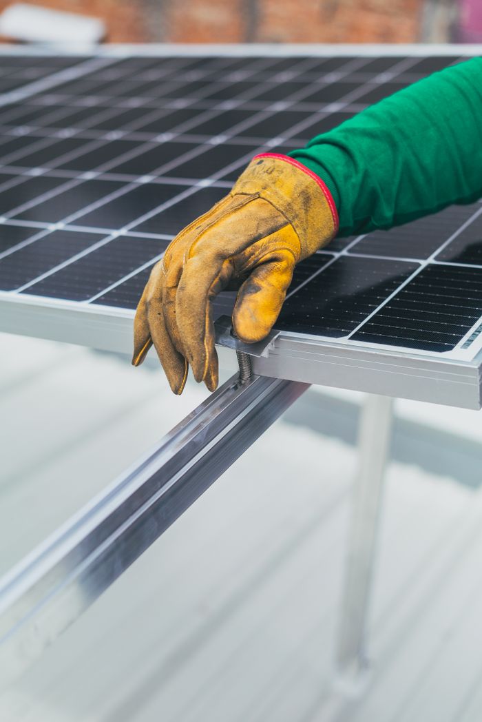 gallery-2 Close-up of a worker's hand in protective glove installing a solar panel.